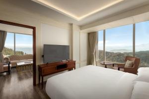 a hotel room with a bed and a flat screen tv at The Greenberry Mountain Resort Narkanda in Nārkanda