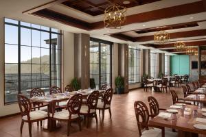 a dining room with tables and chairs and large windows at The Greenberry Mountain Resort Narkanda in Nārkanda