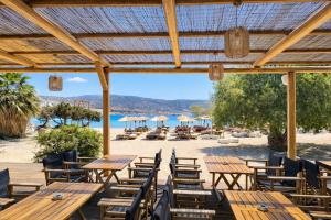 a group of wooden tables and chairs on a beach at Helios Beach Hotel & Bungalows in Karpathos