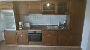 a kitchen with wooden cabinets and a stove and a sink at Ferienreihenhäuser Roswitha in Frauenberg