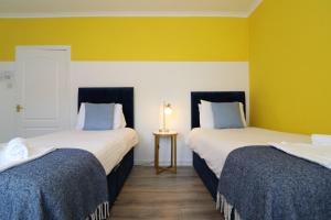 two beds in a room with yellow walls at Signature - Bueno View - Greenock in Greenock