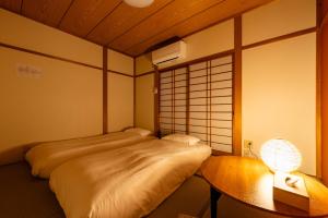 a room with a bed and a table with a lamp at 狐狐 Coco in Kyōto