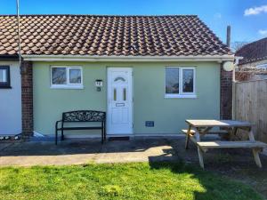a small house with a picnic table and a bench at Mulberry Holiday Home in Great Yarmouth