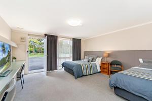 a bedroom with two beds and a desk and a window at Melaleuca Motel in Portland