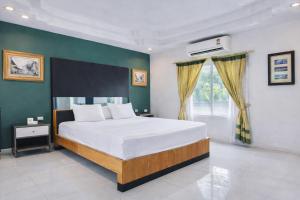 a bedroom with a large white bed and a green wall at The Room Suphanburi in Ban Nong Chaeng