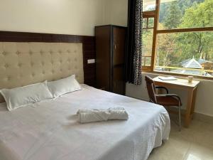 a bedroom with a white bed with a desk and a window at OmiHomeStay Dharamkot McLeodganj in Dharamshala
