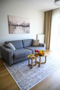 a living room with a blue couch and two tables at Miamare Dziwnow - Komfort Apartment, Panorama, Beach, Pool & Wellness in Dziwnów