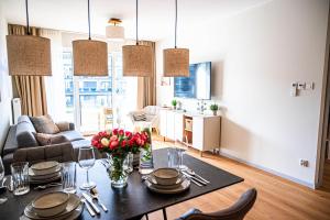 a living room with a dining room table with flowers on it at Miamare Dziwnow - Komfort Apartment, Panorama, Beach, Pool & Wellness in Dziwnów
