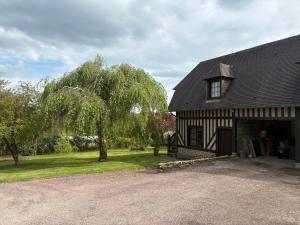 a black and white house with a tree and a driveway at Le Cottage in Cambremer