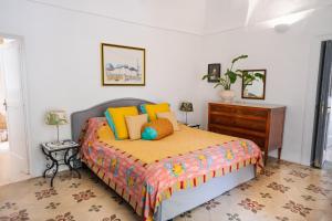a bedroom with a bed with colorful pillows and a dresser at Casa Sam Positano in Positano
