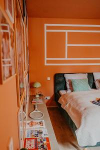 a bedroom with a bed with an orange wall at sleepArt match point in Celle +12 photos