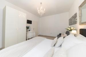 a white bedroom with a large bed and a chandelier at Central Square Luxury Boutique in Zadar