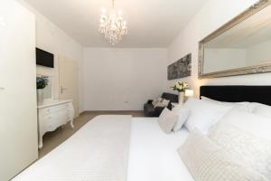 a bedroom with a white bed and a chandelier at Central Square Luxury Boutique in Zadar