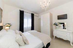 a white bedroom with a white bed and a chandelier at Central Square Luxury Boutique in Zadar