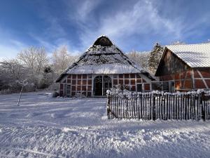 a barn covered in snow with a fence at Kreativ-Kate in Kranenburg