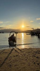 a boat on the beach with the sunset in the background at Bombinhas Summer Beach Apto moderno a 300 m da praia in Bombinhas