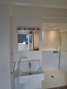 a white bathroom with a sink and a mirror at Studio Les 4 Vents in Tréffiagat