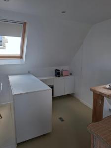 a white kitchen with a counter and a window at Studio Les 4 Vents in Tréffiagat