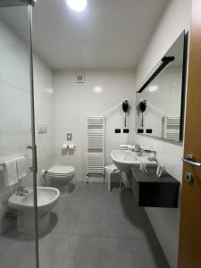 a white bathroom with two sinks and a toilet at Master Hotel in Cadelbosco di Sopra