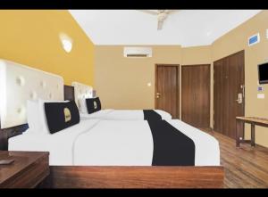 a bedroom with a large white bed with black pillows at Hotel The Pal Palace in Nagpur