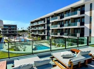 an apartment building with a balcony with a swimming pool at Makia Beach Experience Muro Alto Porto de Galinhas in Ipojuca
