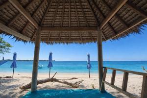 a beach with blue umbrellas and the ocean at Harmony Beachfront Bungalow in Gili Meno