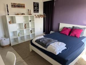 a bedroom with a blue bed with pink pillows at Casa Leopardo in Hasselt
