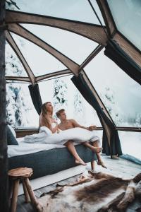 a man and woman sitting on a bed in a tent at Syöte Igloos in Syöte