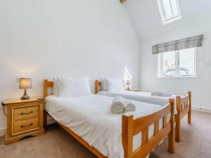 two beds in a bedroom with a nightstand and two windows at 3 Bed in Malton oc-75899 in Amotherby
