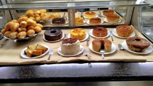 a display case with many different types of cakes and pastries at Augustos Hotel in Santo Antônio de Jesus