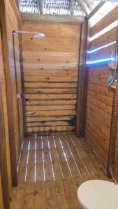 a bathroom with a wooden wall with a toilet at Chalé mirante in Tutóia