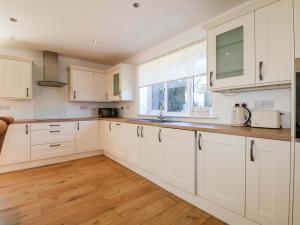 a kitchen with white cabinets and a window at Snowdrop Cottage in Maidstone