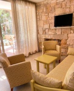 a living room with a couch and chairs and a tv at Hotel Xaloc Playa in Punta Prima