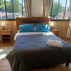 a bedroom with a large bed with blue pillows at Hotel y Cabañas La Magia del Sur in Valdivia