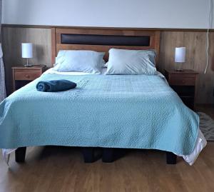 a bed with a blue comforter and two night stands at Hotel y Cabañas La Magia del Sur in Valdivia +3 photos