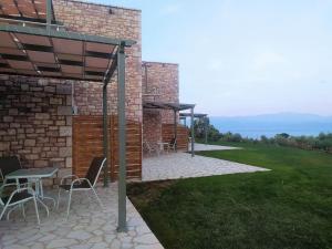 a patio with chairs and tables and a brick building at Stone Bay Houses in Messinia Kalamaki Beach Area in Chrani