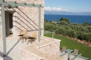 a patio with a table and chairs and the ocean at Stone Bay Houses in Messinia Kalamaki Beach Area in Chrani +54 photos