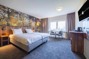 a hotel room with a large bed and a table at Fletcher Hotel-Restaurant Paasberg in Lochem