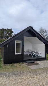 a black and white building with a picnic table in it at Henneby Camping - hytter in Henne Strand +6 photos
