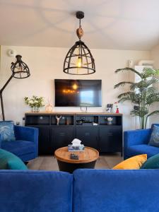 a living room with blue couches and a tv at Maison La Bullette à 10 min de Pontarlier in Bulle