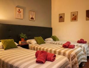 a room with three beds with red towels on them at ViaVia Buenos Aires GuestHouse in Buenos Aires