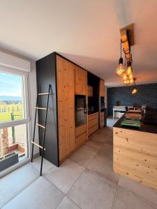 a kitchen with wooden cabinets and a large window at Maison La Bullette à 10 min de Pontarlier in Bulle