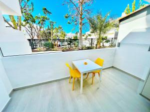 a small white table and two yellow chairs on a balcony at Modern Studio with Pool & Terrace Playa de las Américas, Tenerife in Playa de las Americas