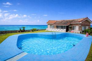 a house with a large swimming pool in front of the ocean at 478 retreat in Yoron