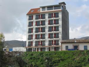 a tall white building with a red roof at Hotel Makita in Muquiyauyo