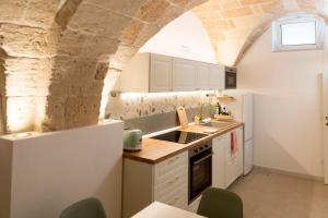 a kitchen with white cabinets and a stone wall at Suite Bobo in Monopoli +12 photos