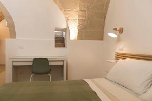 a bedroom with a bed and a desk and a chair at Suite Bobo in Monopoli