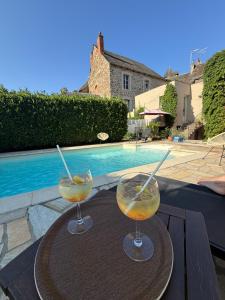 two drinks on a table next to a swimming pool at Auberge Saint Fleuret in Estaing