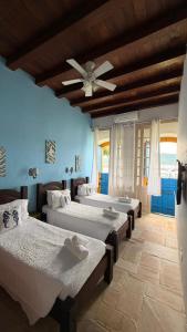 a bedroom with three beds and a ceiling fan at Pousada do Cais in Paraty