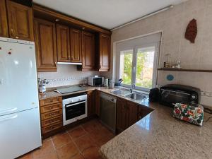 a kitchen with wooden cabinets and a white refrigerator at Finca Bellavista de Gredos in Madrigal de la Vera